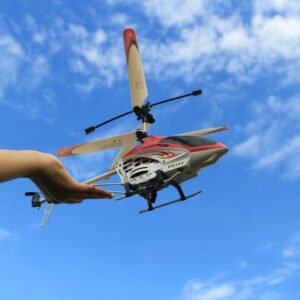 Hand launching a remote control helicopter against a bright blue sky.