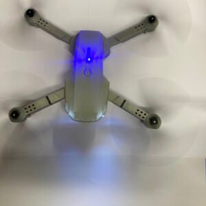 Top-down view of a gray quadcopter drone with rotating propellers and glowing blue LED indicator lights.