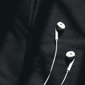 Close-up of white wired earphones on dark fabric creating a minimalist aesthetic.