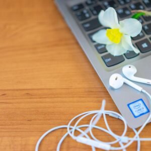 White earphones and a daffodil on a laptop, blending technology and nature.