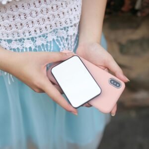 Close-up of a woman holding a smartphone and power bank, showcasing technology and connectivity.