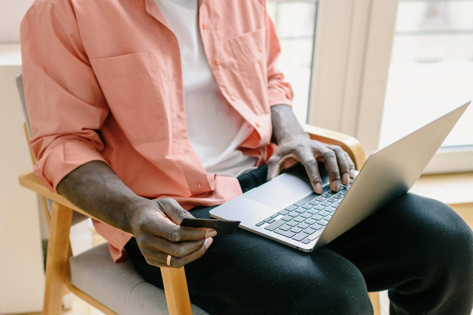 pexels photo 7301122 7301122 A man sitting with a laptop and credit card, browsing online indoors during the day.