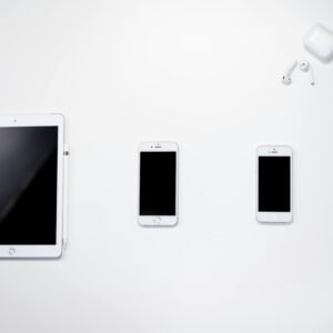 Flat lay of smartphone, tablet, and earphones arranged on a white surface for a clean, minimalist aesthetic.