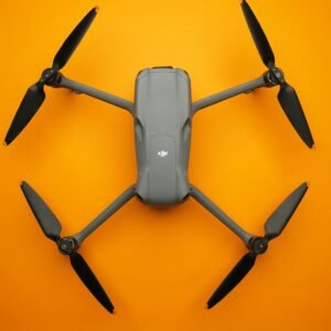 Top view of a sleek folding drone isolated on a vibrant orange background.