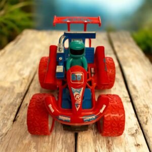 A red 4WD racing stunt car toy with a blue driver figure, large red textured tires, and "Speed 68" decals, performing a 360-degree rotation stunt on a wooden surface.