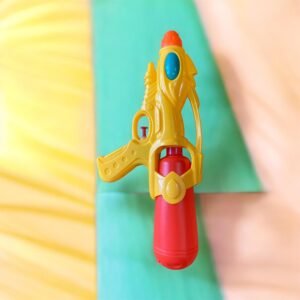 A yellow and red small water spray bottle toy with a blue decorative accent and orange nozzle, held against a soft green and yellow background.