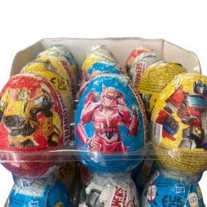 A bulk retail box of 24 individually wrapped 20g Transformers chocolate eggs featuring Optimus Prime and Bumblebee with a surprise collectible toy inside.